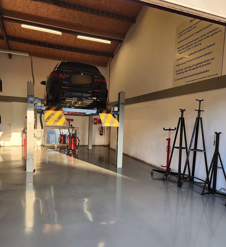 De hal van Franky's Garage: een auto op de brug, assteunen langs de muur en een glanzende vloer